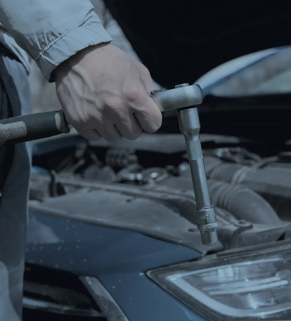 Mechaniker loest mit der Knarre eine Schraube am Motor